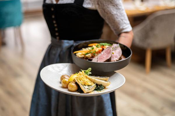 Eine Kellnerin mit zwei Tellern mit feinen Hauptgängen in der Hand