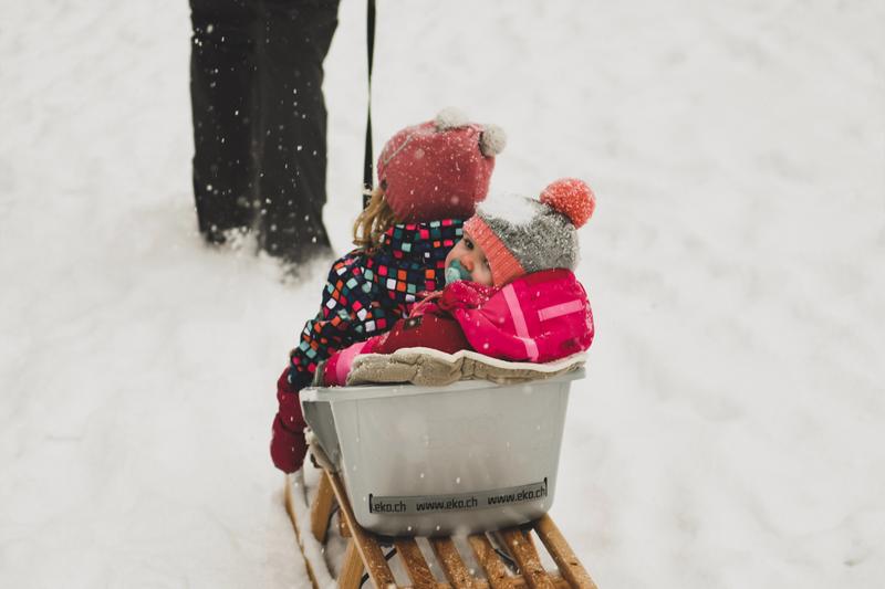 Zwei Kinder sitzen in einem Rodel