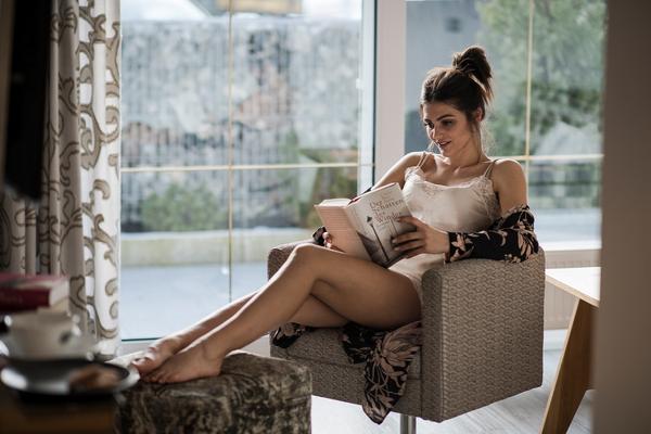 Eine Frau sitzt im Sessel des Hotelzimmers und liest