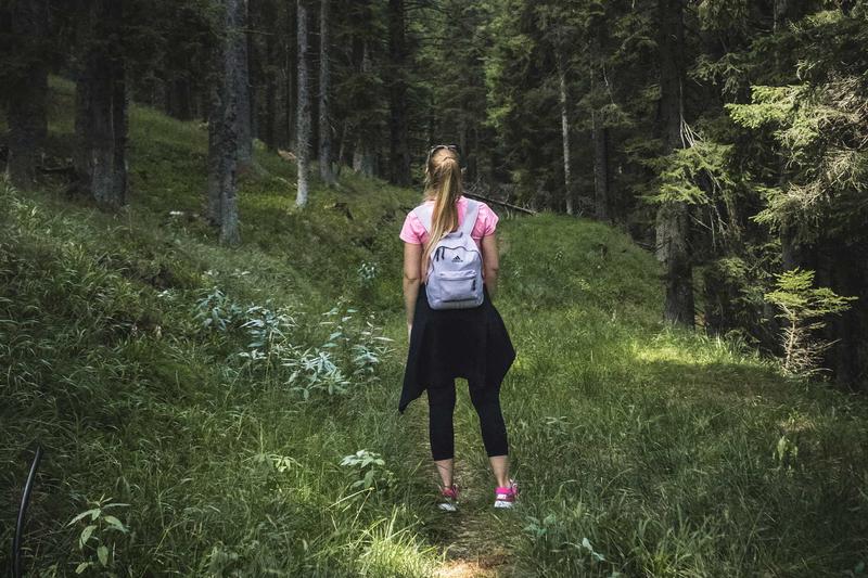 Eine Wanderin steht mit einem Rucksack im Wald