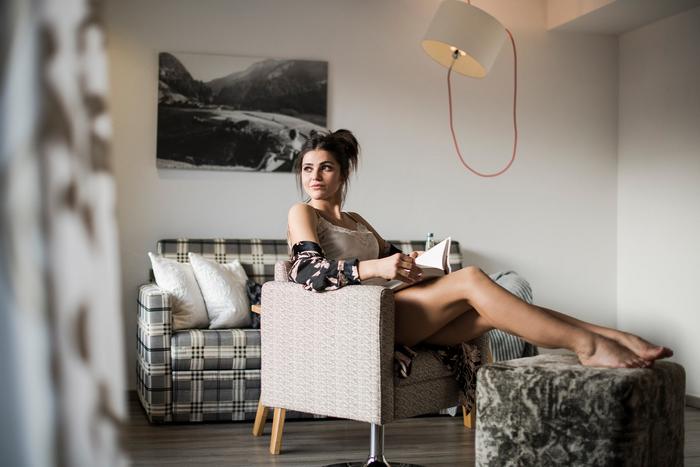 Eine Frau sitzt im Sessel des Hotelzimmers und liest