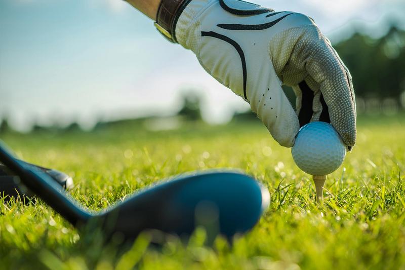 Detailaufnahme eines Golfers, der seinen Golfball zum Abschlag platziert