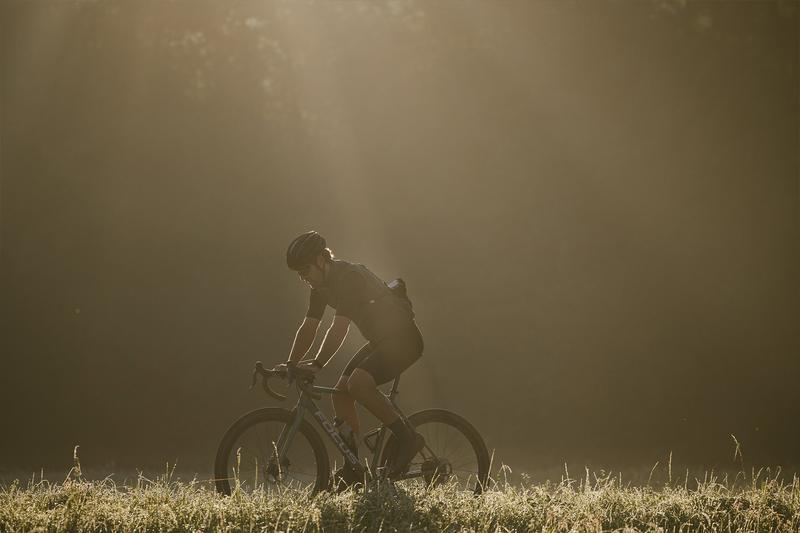 Ein Mann fährt mit seinem Gravelbike durch einen morgendlichen Wald