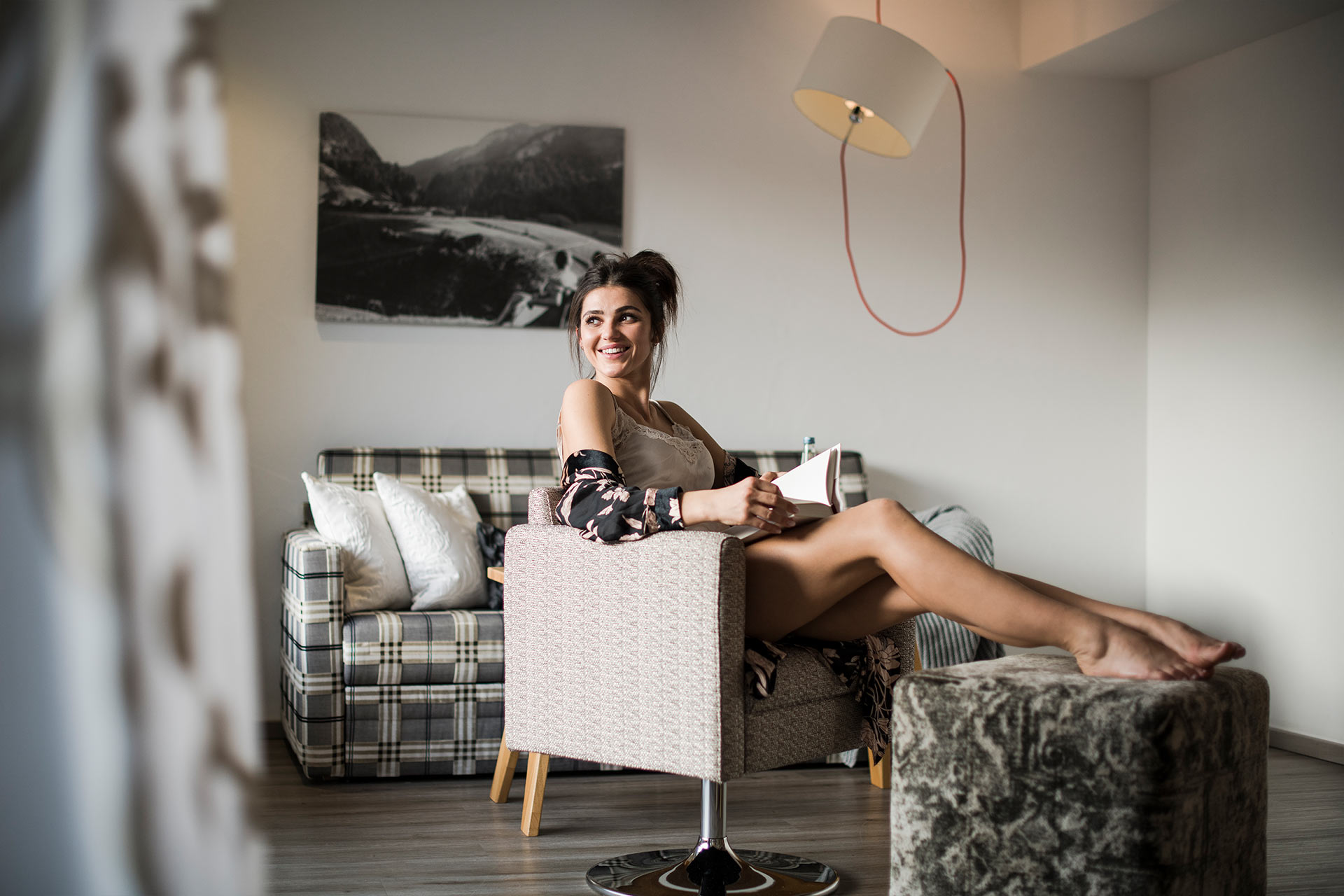Eine Frau sitzt im Sessel des Hotelzimmers und liest